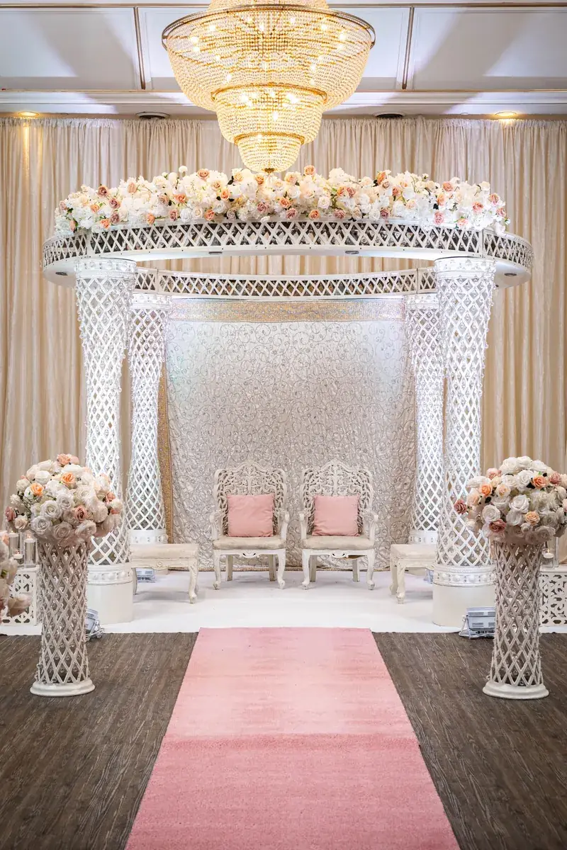 Palazzo Mandap under a crystal chandelier with a pink aisle runner