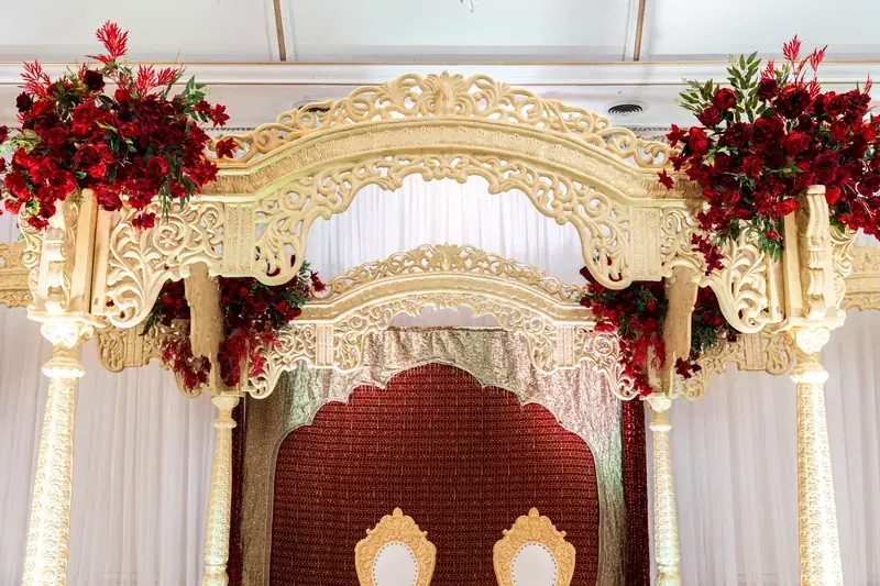 Rangeela Mandap: gold arch with red floral clusters