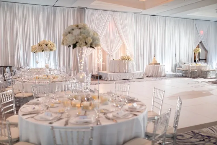 White draped ballroom with round tables and tall centrepieces