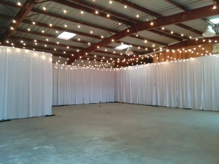 White wall draping around an open hall with string lights